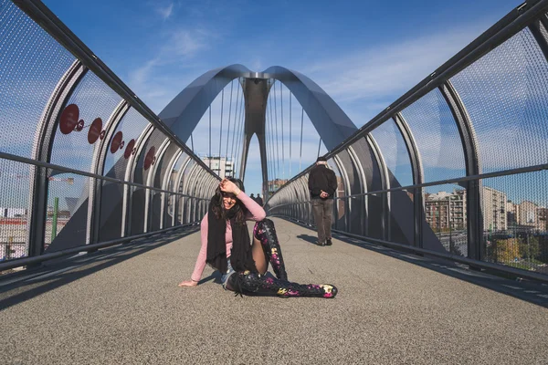 Beautiful young brunette posing on a bridge — Stock Photo, Image