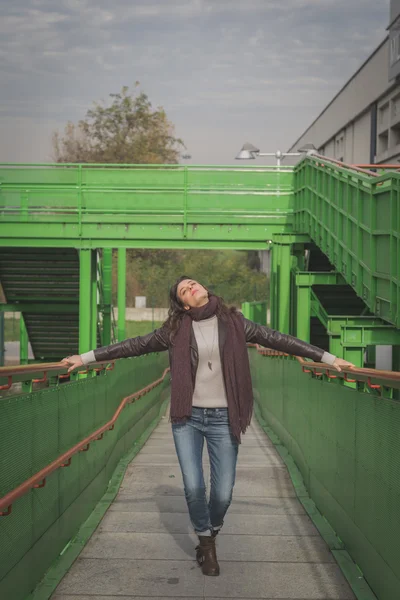 Beautiful young brunette posing on a bridge — Stock Photo, Image