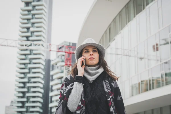 Beautiful young brunette talking on phone in the city streets — Stock Photo, Image