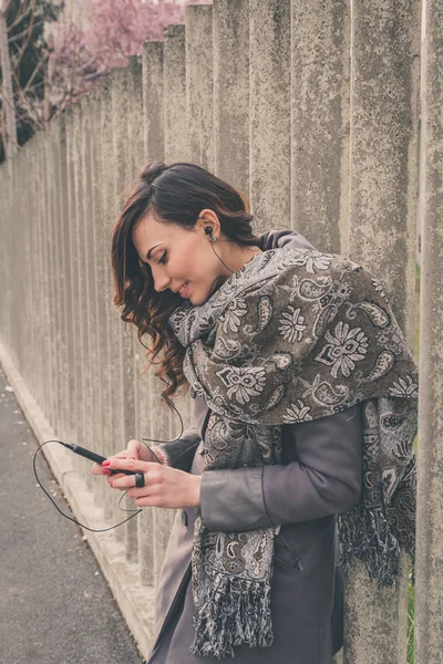 Hermosa chica escuchando música en un contexto urbano — Foto de Stock