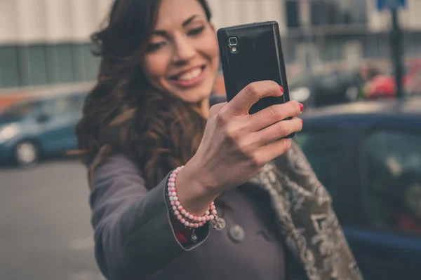 Hermosa chica tomando una selfie en un contexto urbano — Foto de Stock