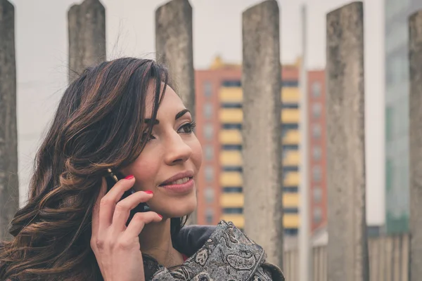 Belle fille parlant au téléphone dans un contexte urbain — Photo