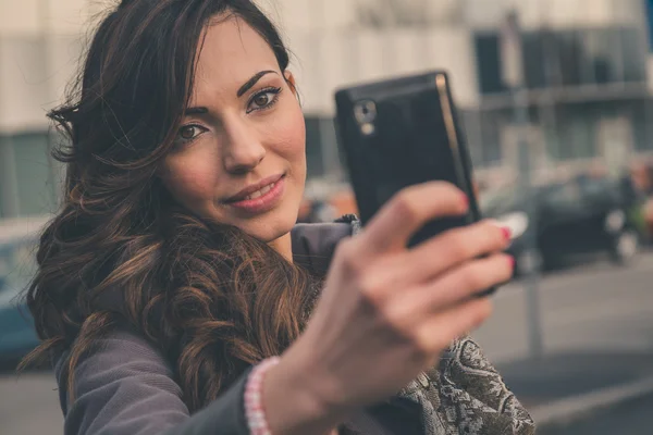 Belle fille prenant un selfie dans un contexte urbain — Photo