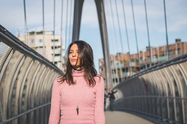 Beautiful young brunette posing on a bridge — Stock Photo, Image