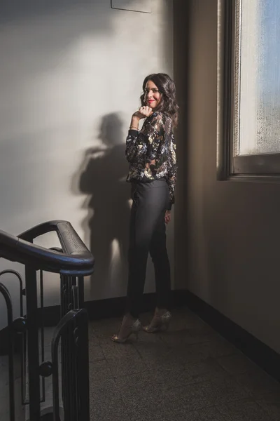 Retrato de uma bela jovem morena posando ao lado de uma janela — Fotografia de Stock