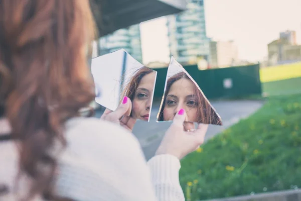 Vacker flicka tittar på sig själv i en spegel — Stockfoto