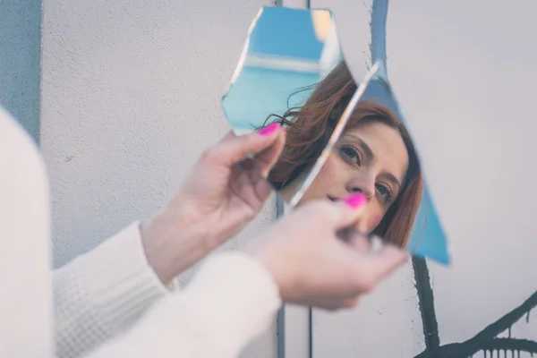 Beautiful girl looking at herself in a mirror