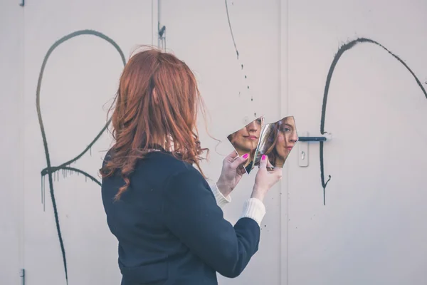 Beautiful girl looking at herself in a mirror — Stock Photo, Image