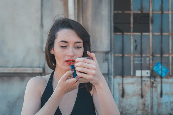 Beautiful brunette making up in an industrial context — Stock Photo, Image