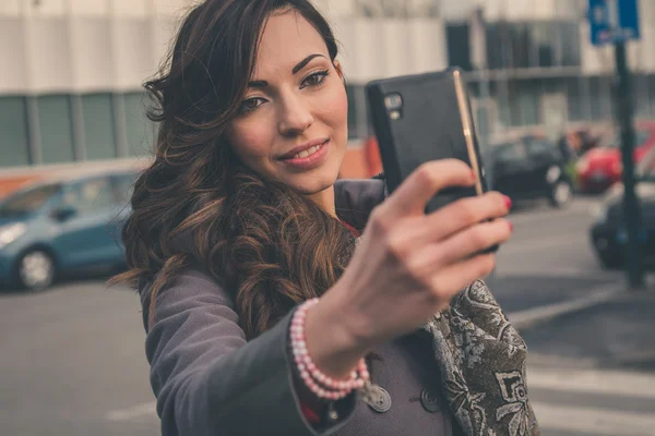 Krásná dívka s selfie v městském kontextu — Stock fotografie