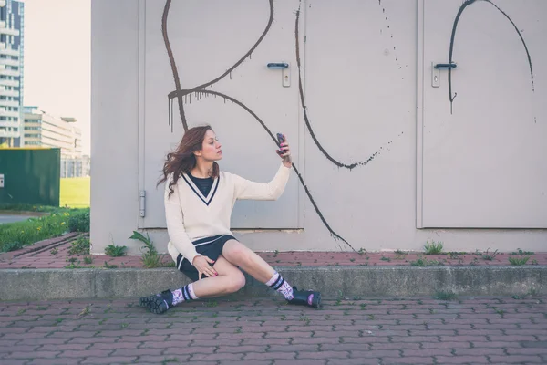 Vacker flicka med en selfie i en stadsmiljö — Stockfoto