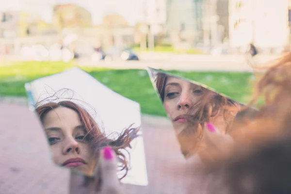 Beautiful girl looking at herself in a mirror — Stock Photo, Image