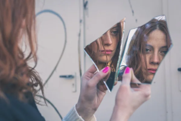 Beautiful girl looking at herself in a mirror — Stock Photo, Image