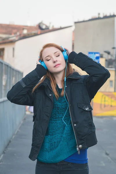 Beautiful girl with headphones posing in the city streets — Stock Photo, Image