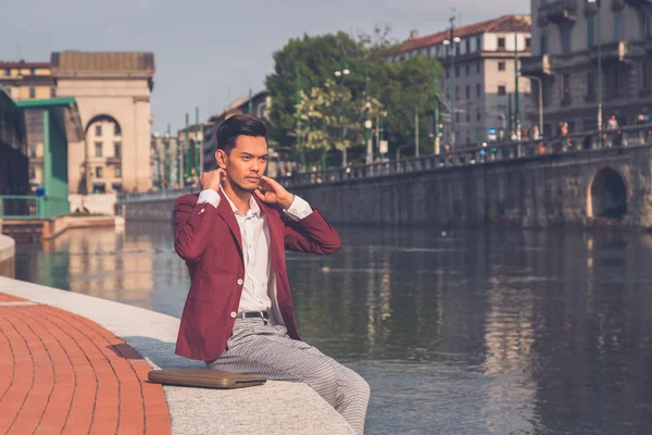Handsome Asian model sitting by an artificial basin — Stock Photo, Image