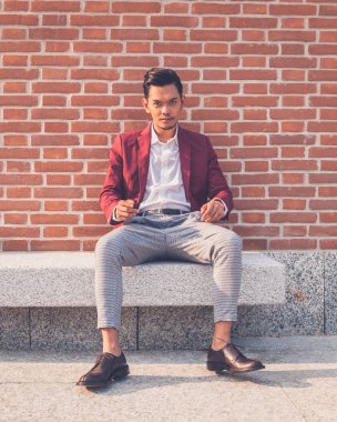 Şehir sokakta oturan yakışıklı Asya modeli