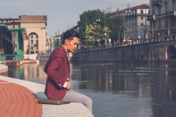 Handsome Asian model sitting by an artificial basin — Stock Photo, Image