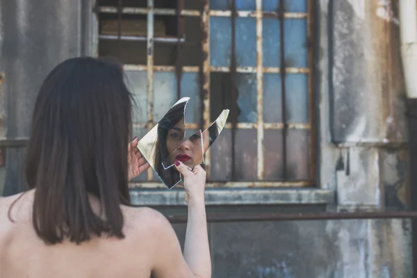 Beautiful brunette looking at herself in a mirror — Stock Photo, Image