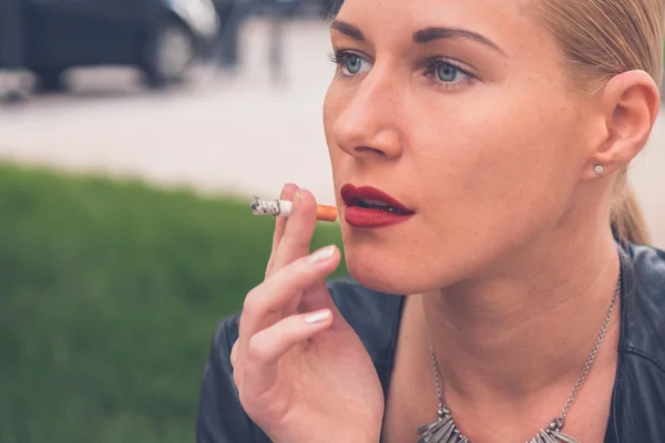 Beautiful girl smoking in the city streets — Stock Photo, Image