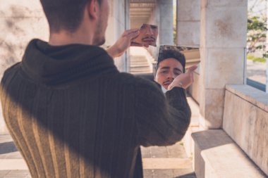 Genç adam kendisi de kırık aynaya bakmak