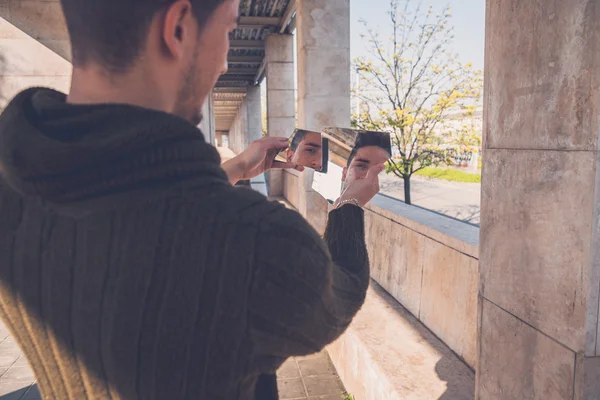 Ung man tittar på sig själv i en trasig spegel — Stockfoto