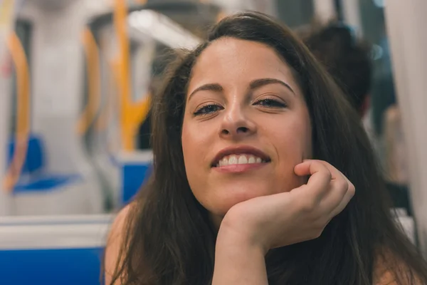 Gyönyörű kanyargós lány pózol egy metró kocsiban — Stock Fotó