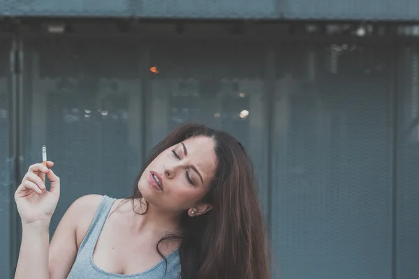 Beautiful curvy girl smoking a cigarette in an urban context — Stock Photo, Image