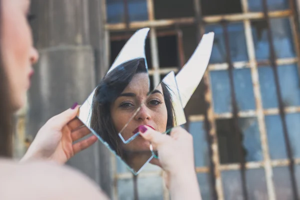 Beautiful brunette looking at herself in a mirror — Stock Photo, Image