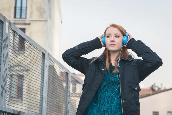 Krásná dívka s sluchátka pózuje v ulicích města — Stock fotografie