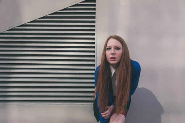 Bella rossa ragazza in posa in un contesto urbano — Foto Stock