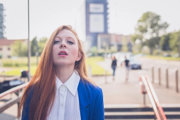 Bella rossa ragazza in posa in un contesto urbano — Foto Stock