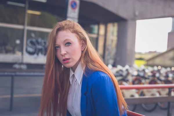 Vacker rödhårig tjej poserar i en stadsmiljö — Stockfoto