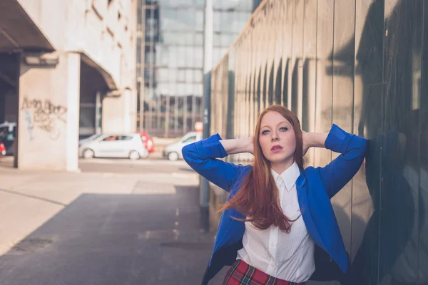 Bella rossa ragazza in posa in un contesto urbano — Foto Stock