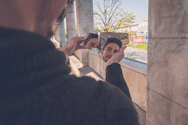 Ung man tittar på sig själv i en trasig spegel — Stockfoto