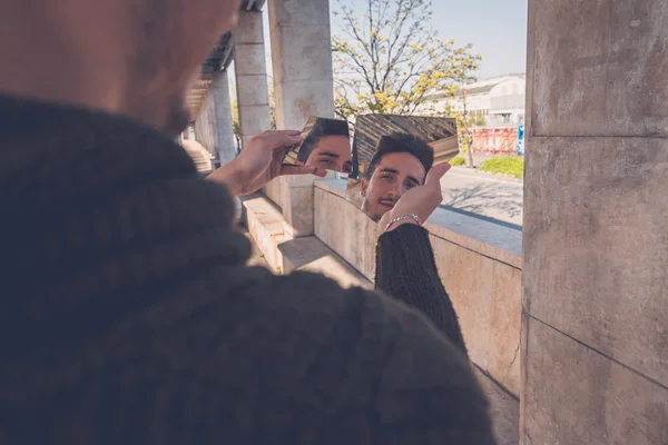 Joven mirándose a sí mismo en un espejo roto — Foto de Stock