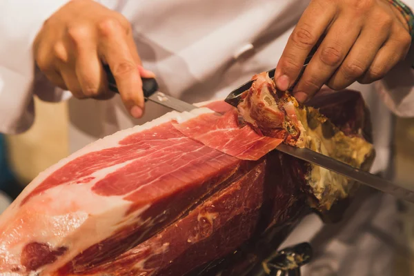 Man slicing raw ham inside Spain pavilion at Expo 2015 in Milan, — Stock Photo, Image