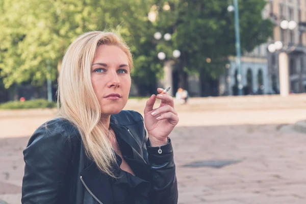 Beautiful girl smoking in the city streets — Stock Photo, Image