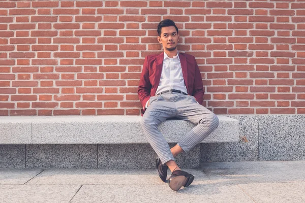 Handsome Asian model sitting in the city streets — Stock Photo, Image