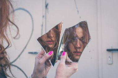 Beautiful girl looking at herself in a mirror clipart