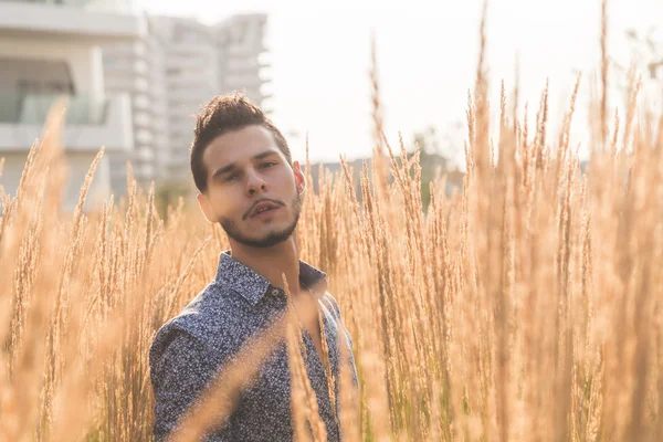 Jovem bonito homem posando em um campo — Fotografia de Stock