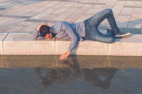 Jonge knappe man kijken naar zichzelf in het water — Stockfoto