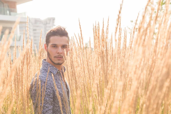 Jovem bonito homem posando em um campo — Fotografia de Stock