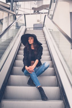 Güzel kız bir yürüyen merdiven üzerinde poz