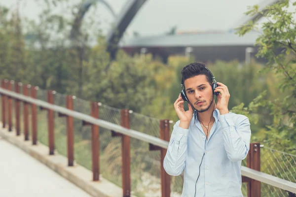 Jovem homem bonito ouvindo música em um contexto urbano — Fotografia de Stock