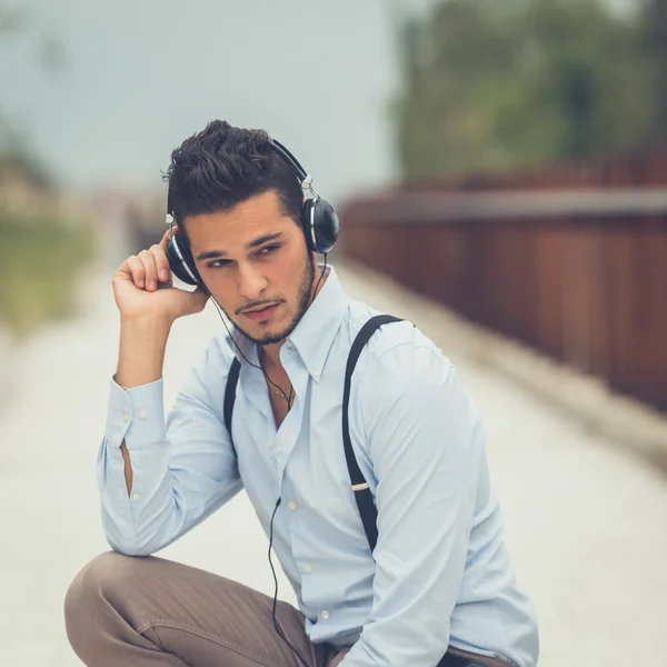 Jovem homem bonito ouvindo música em um contexto urbano — Fotografia de Stock