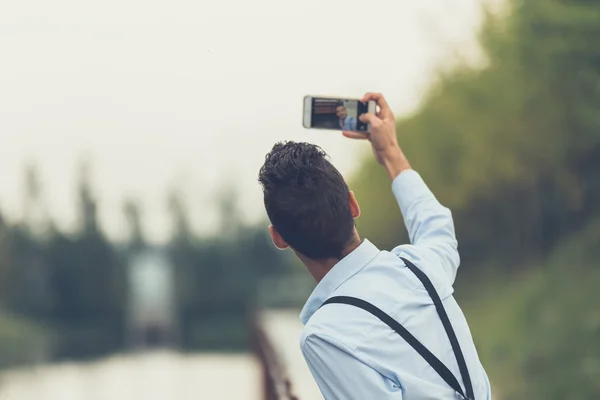 Yakışıklı delikanlı bir nehir kenarında bir selfie alarak — Stok fotoğraf