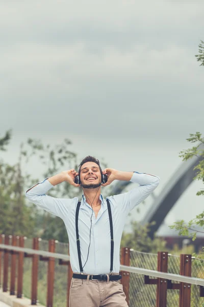 Jovem homem bonito ouvindo música em um contexto urbano — Fotografia de Stock