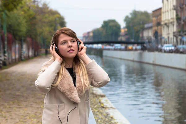 Menina bonita ouvir música com fones de ouvido em um co urbano — Fotografia de Stock