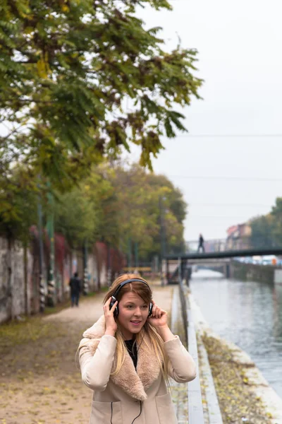 美丽的女孩，听听音乐用耳机在城市的 co — 图库照片