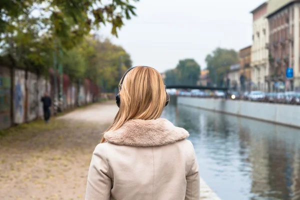 Hermosa chica escuchando música con auriculares en un co urbano — Foto de Stock